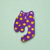 Purple cat-shaped patch with yellow spots on a light green background
