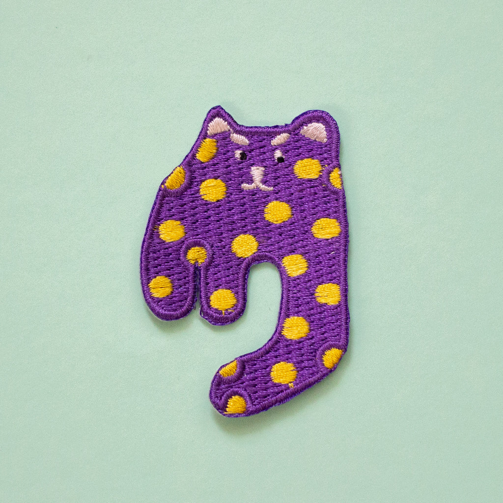 Purple cat-shaped patch with yellow spots on a light green background