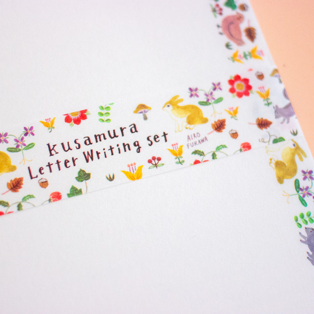 A close-up of a letterset with a white background and colourful woodland illustrations including flowers, leaves, acorns, a rabbit, and a bird.