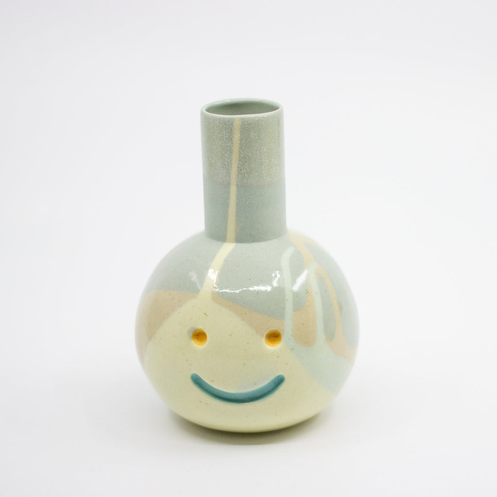 Ceramic vase with a smiley face design on a white background