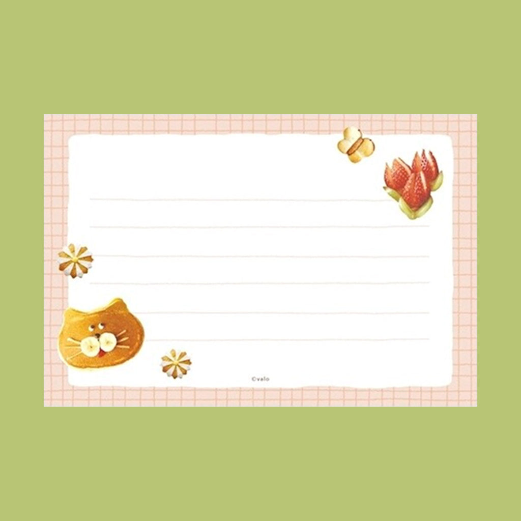 A rectangular lined writing card with cute illustrations, featuring a pink grid border, a yellow cat face on the bottom left, small flowers, a butterfly, and a strawberry on the right side, set against a solid light green background.