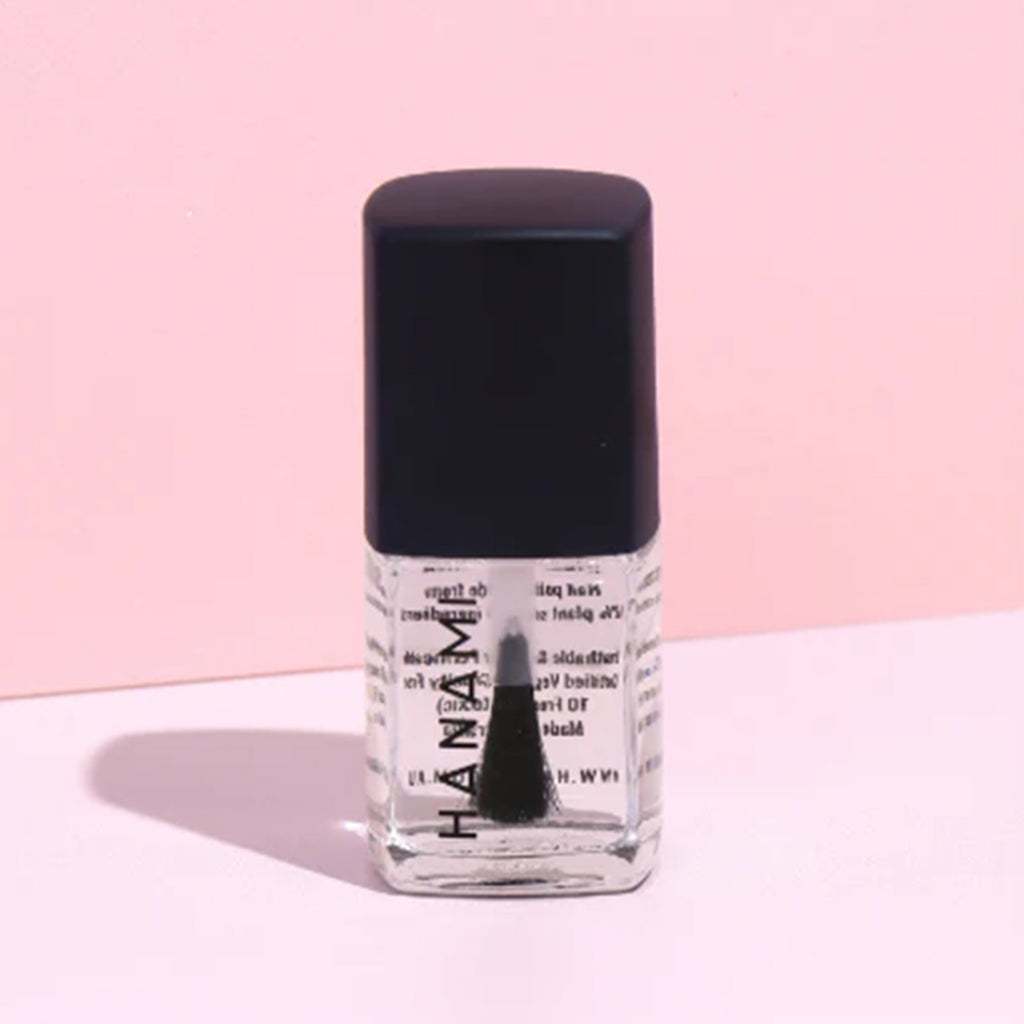 Nail polish bottle with black cap on a pink background