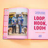 Open book showing two person wearing a colourful sweater with two dogs, on a peach background.