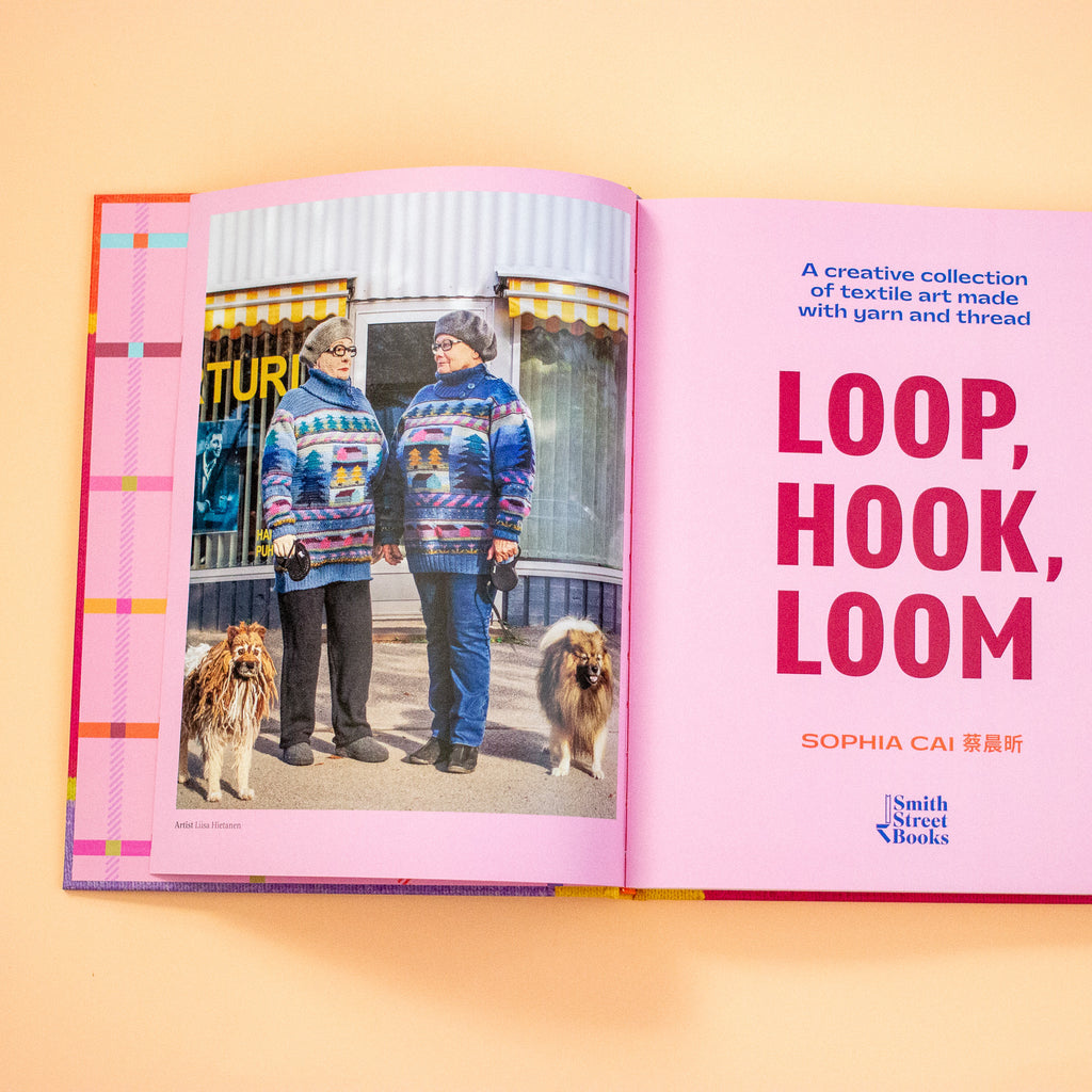 Open book showing two person wearing a colourful sweater with two dogs, on a peach background.