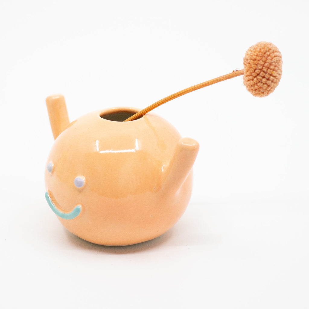 Sideview of the Lucia vase holding a flower. 