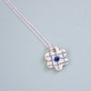 Necklace with a blue and white checkered flower pendant on a light blue background