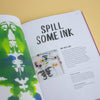 Book with writing and pictures of ink art on a yellow background