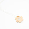 Sterling silver necklace featuring a light peach ceramic flower-shaped pendant with a white dot in the centre, displayed on a white background.