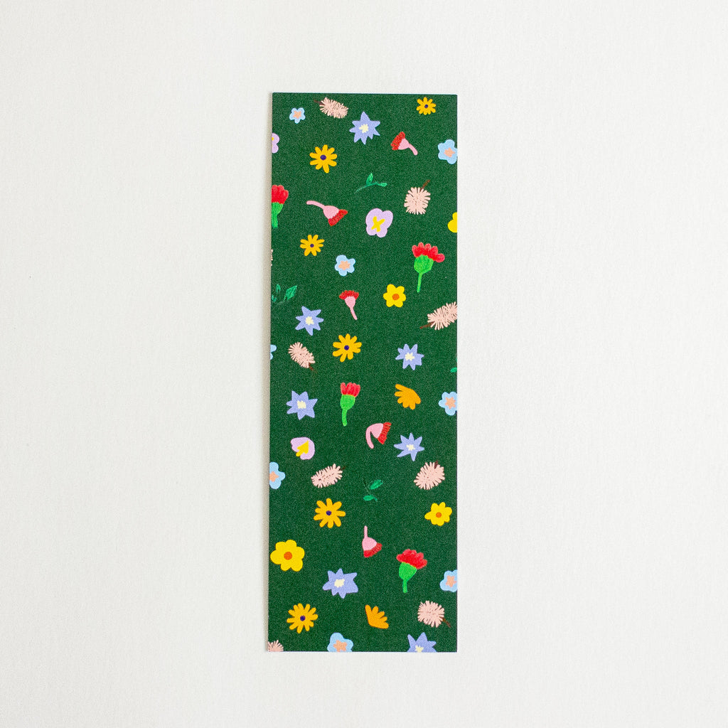 A rectangular dark green bookmark, featuring a colourful pattern of small flowers displayed flat against a light off-white background.