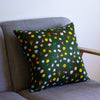 A Front view of the meadow cushion cover on a couch. Multicoloured and varied flowers on a dark green background. 