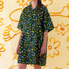 A front view of the Meadow linen dress, with multicoloured flower designs on a meadow green background. 