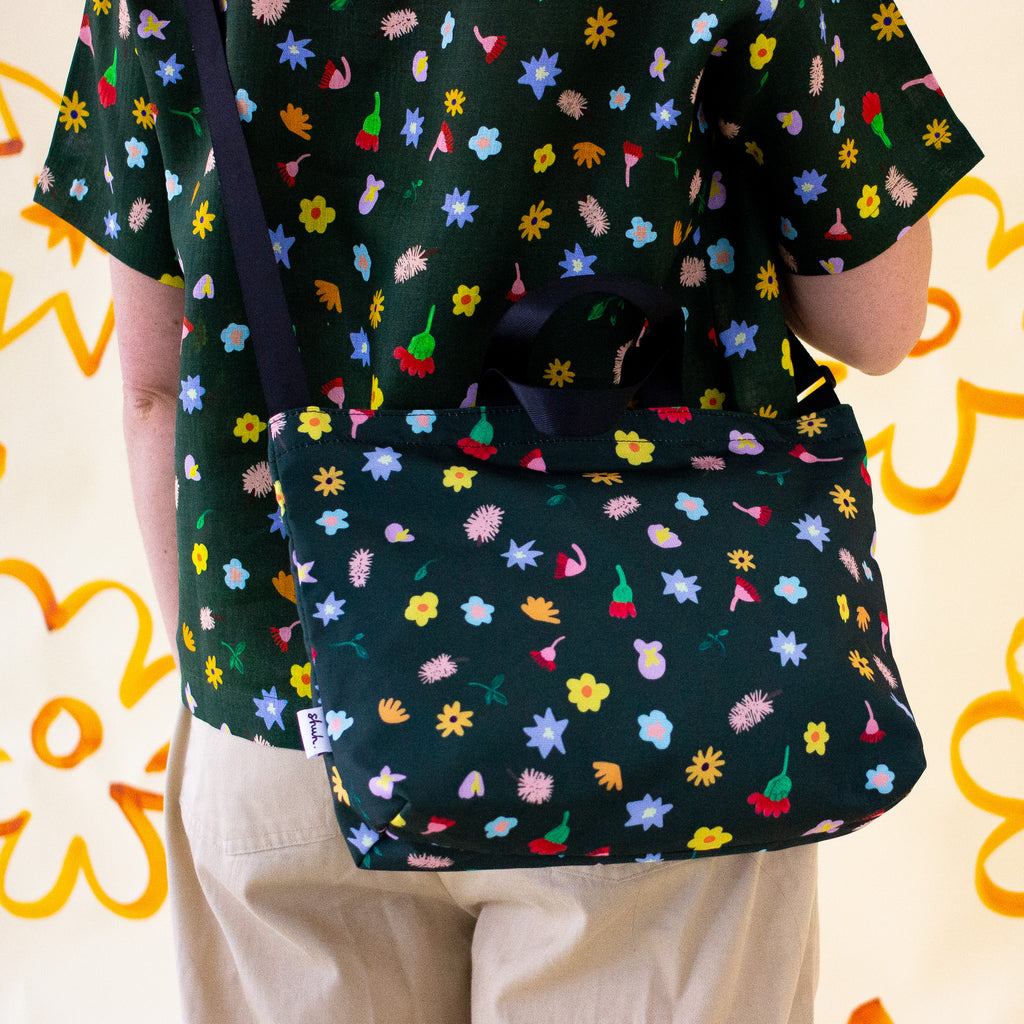 The meadow easy bag being carried as a Shoulder bag. Multicoloured flowers on a meadow green background.