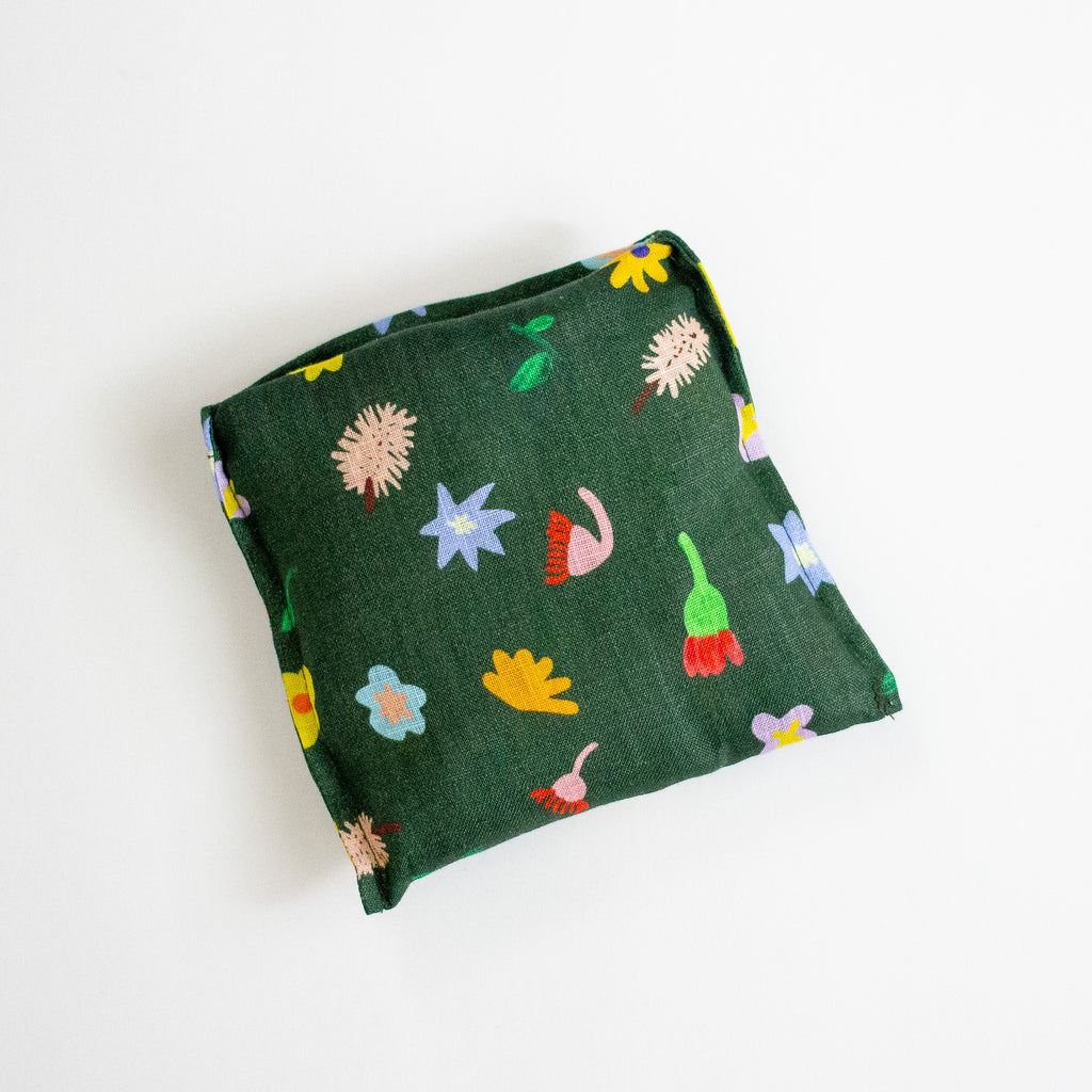 A square fabric pouch in dark green with a colourful floral and botanical pattern, shown on a plain white background.