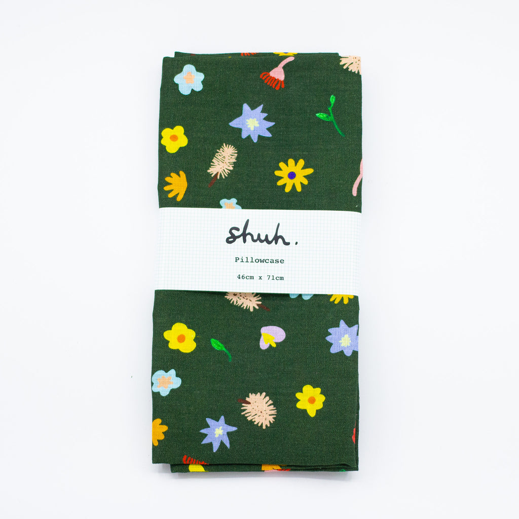 A Top view of the Meadow pillow case, folded in packaging. Illustrated wildflowers on a meadow green background. 