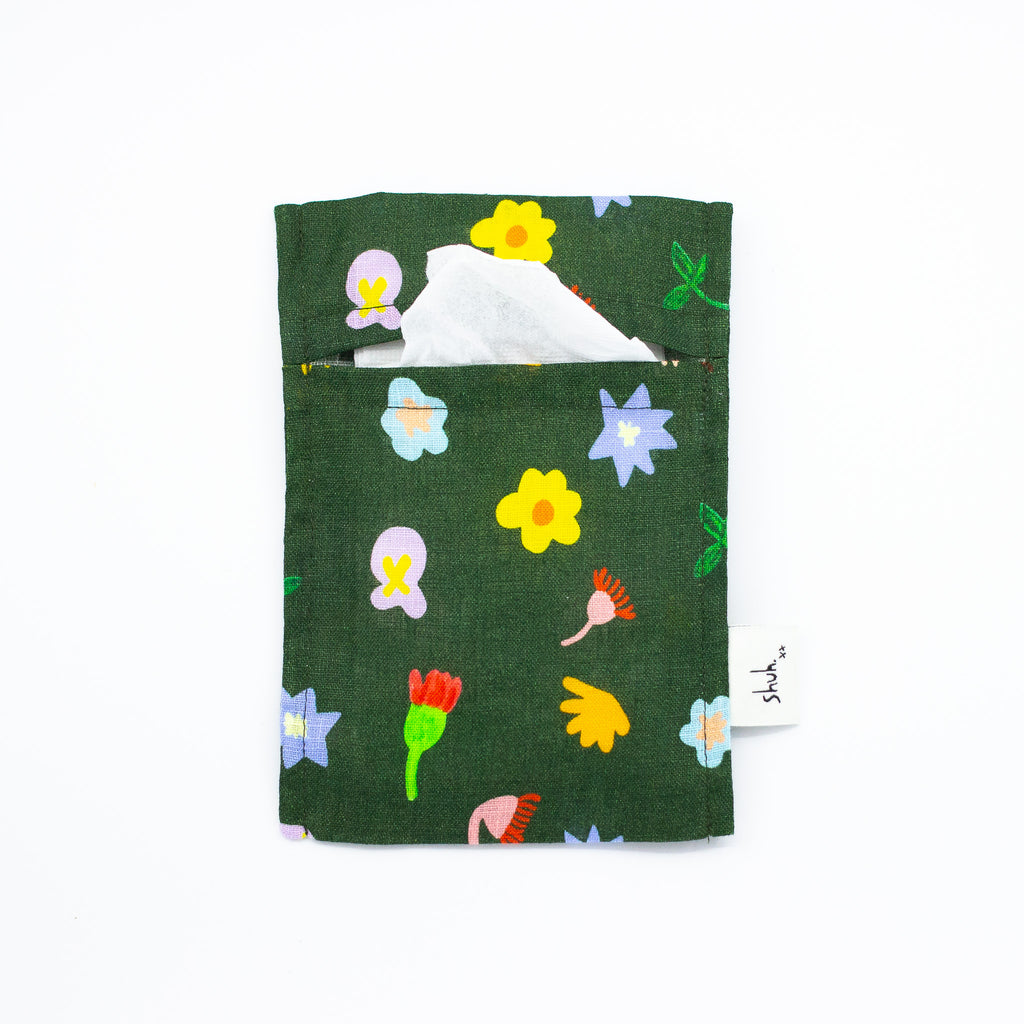 Front view of the meadow pocket tissue holder. In use holding tissues. Illustrated wildflowers on a meadow green background