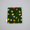 Green fabric square with colourful floral patterns on a grey background