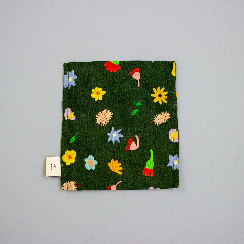 Green fabric square with colourful floral patterns on a grey background
