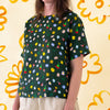 A side view of a model wearing the Meadow linen top. Various flower designs over a meadow green background. 