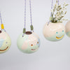 Set of hanging ceramic planters with smiley face designs on a light gray background
