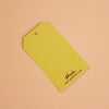A yellow paper hang tag with a hole at the top left, printed with the brand name 'shuh.' and website 'www.shuh.com'