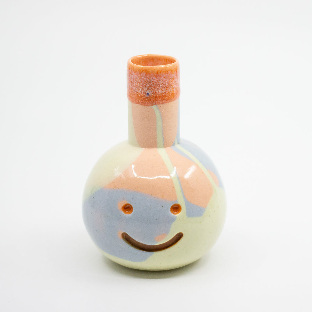 Ceramic vase with a face design on a white background