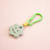Green keychain with a smiley face charm on a pink background