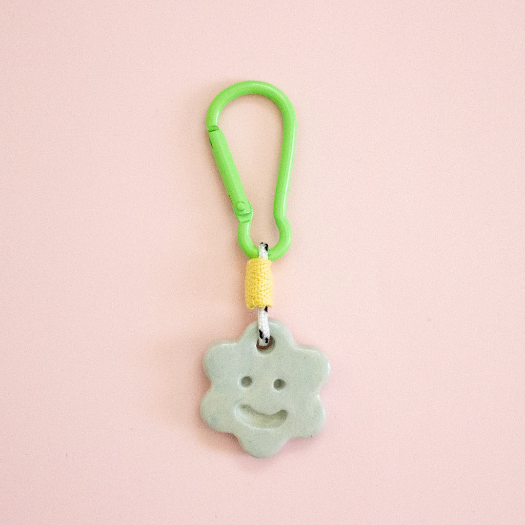 Star-shaped keychain with a smiley face on a pink background