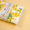 A folded white fabric handkerchief with a yellow and green floral print, wrapped in a paper band labeled 'HAIKARA HANDKERCHIEF made in JAPAN', on a solid pale yellow background.