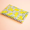 A spiral-bound notebook titled 'SEAL COLLECTION NOTE' featuring a yellow mimosa floral pattern on a light grey cover, displayed on a soft peach background.