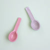 Two pink ceramic spoons on a light green background