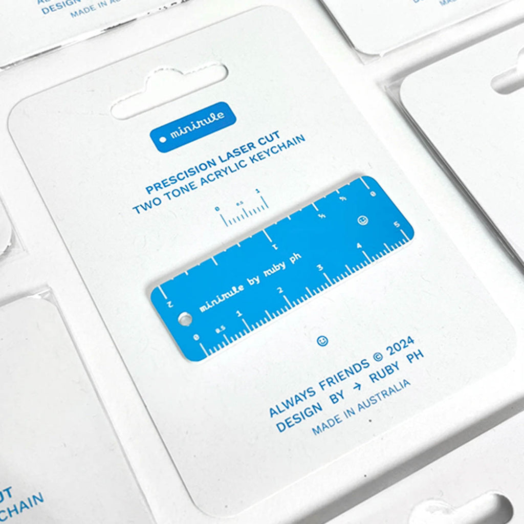 A blue and white acrylic keychain ruler displayed on its white retail packaging card.