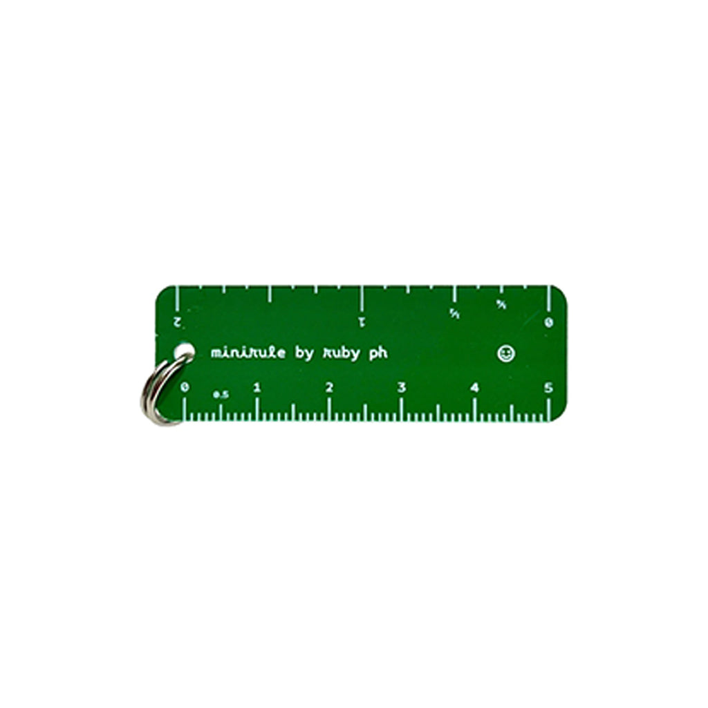 A green rectangular pocket ruler with white markings and text reading 'minimize by ruby ph', attached to a silver metal key ring, shown on a plain white background.