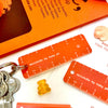 Orange plastic pocket rulers with white measurement markings and the text 'minirule by ruby ph' printed on them, shown attached to a keyring with keys on a white surface alongside small decorative items.