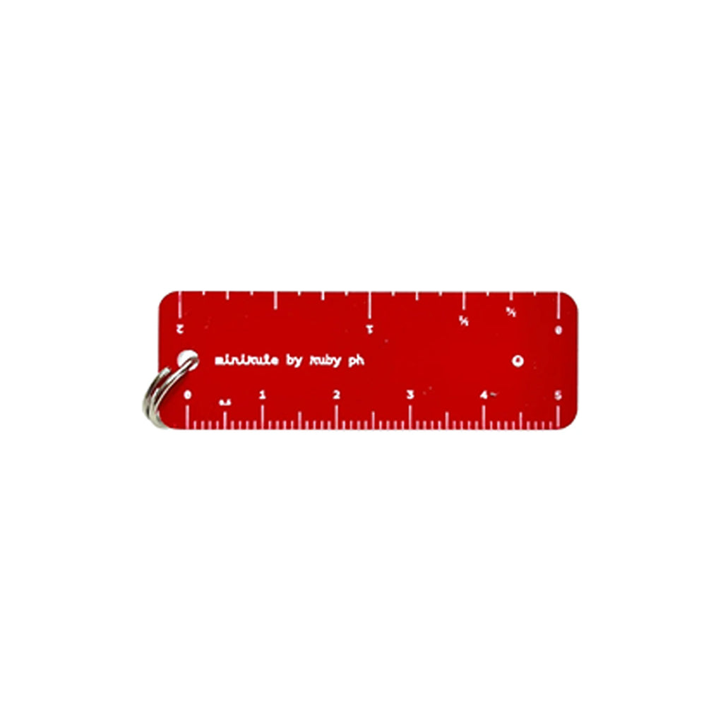 A red rectangular pocket ruler with white markings and the text 'minirule by ruby ph' on a white background, attached to a silver metal key ring.