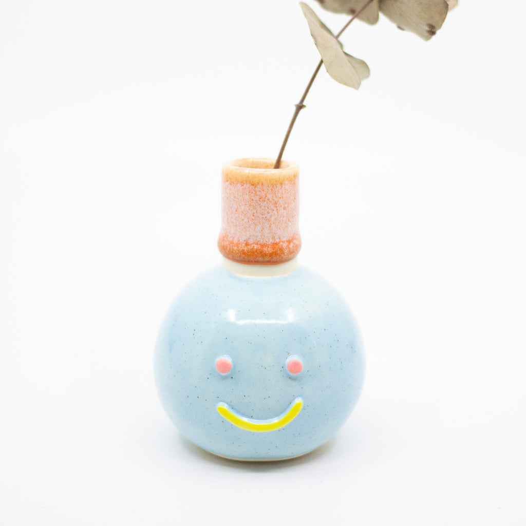 Front view of the Momo Vase holding a leaf. Blue colours. 