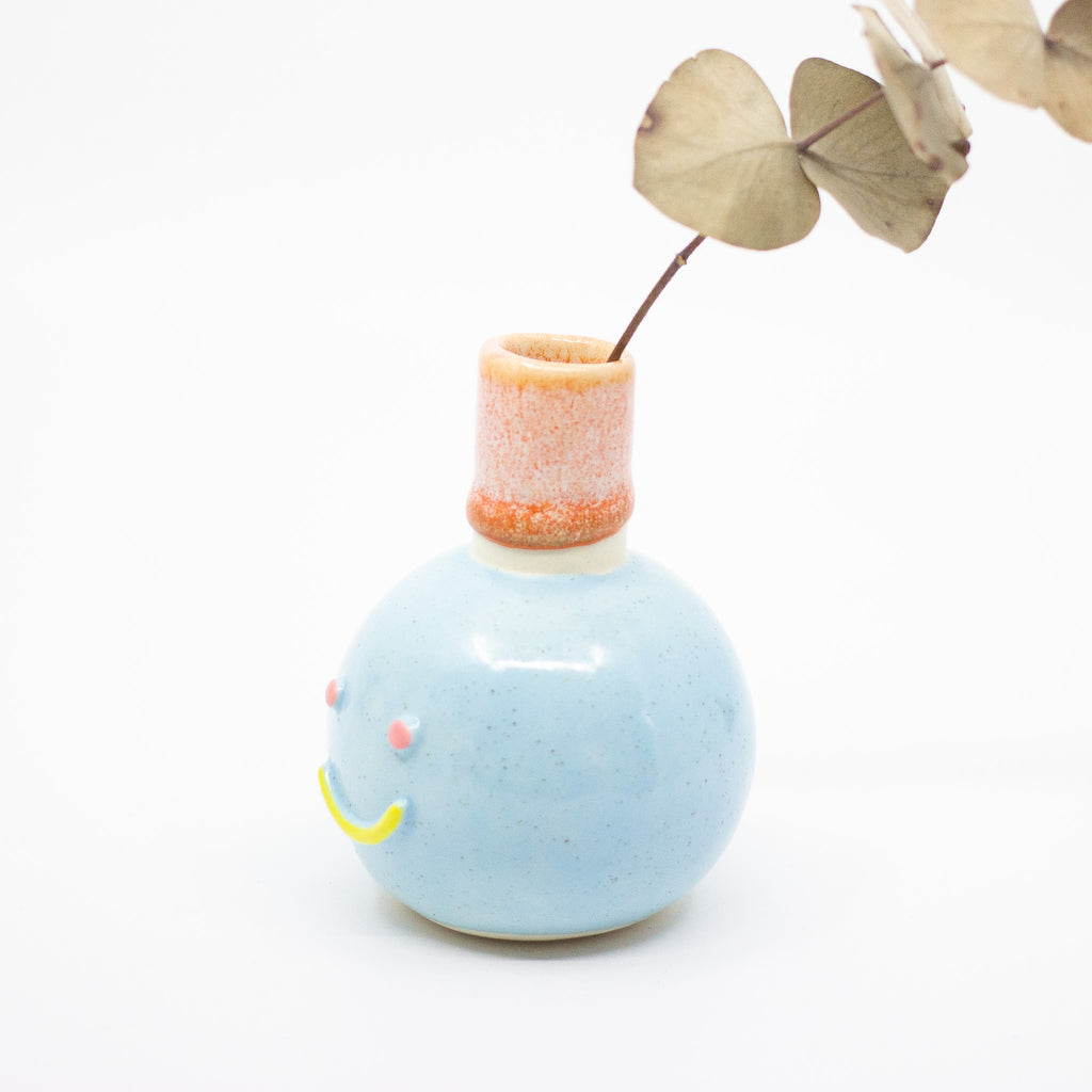 Side view of the momo vase holding a leaf. Blue colours. 