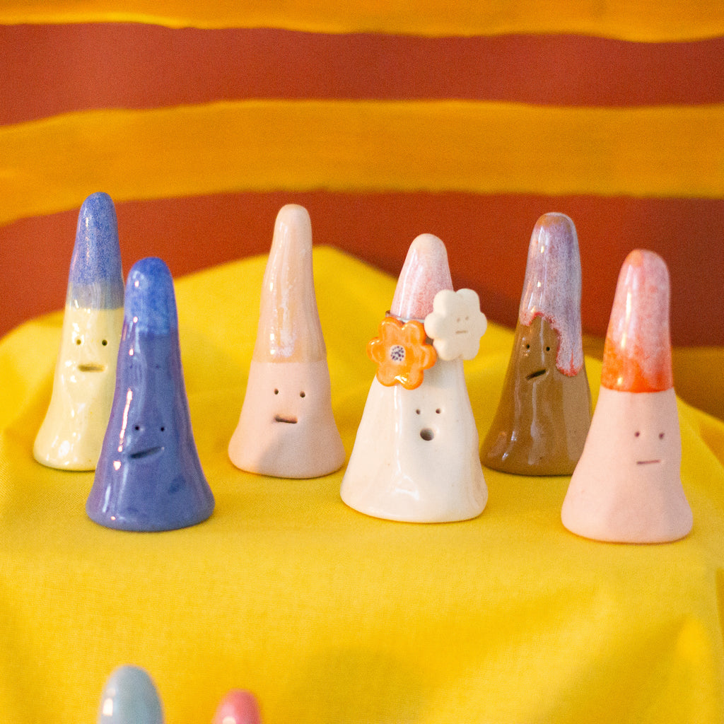A closeup picture of 6 ring holders, 1 holding rings. They all have different faces and expressions, with different colours and glazes. 