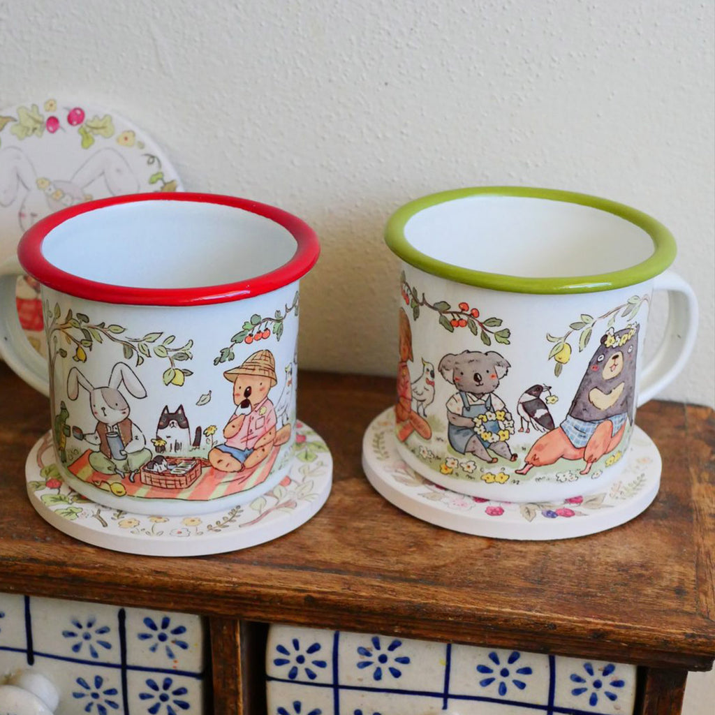Two mugs with animal illustrations on a wooden surface.