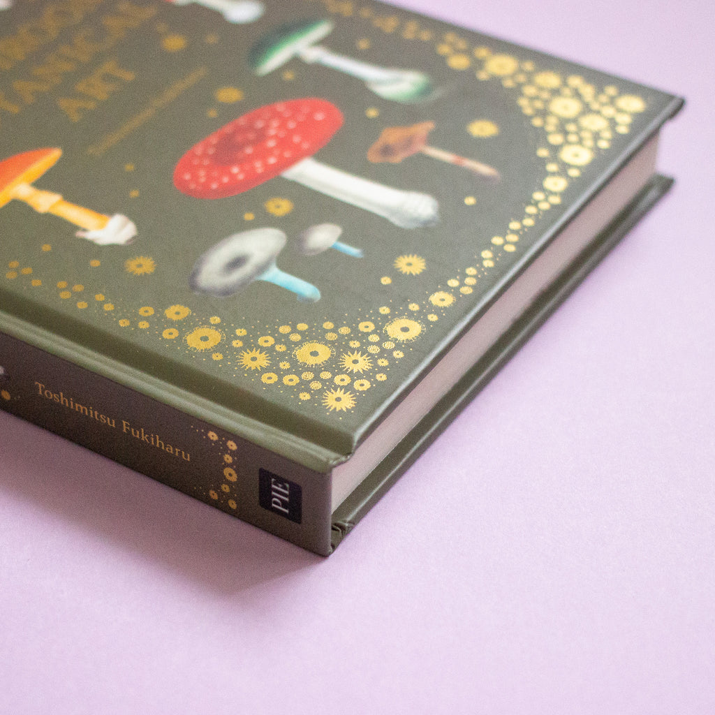 Book with mushroom illustrations on a green cover against a purple background