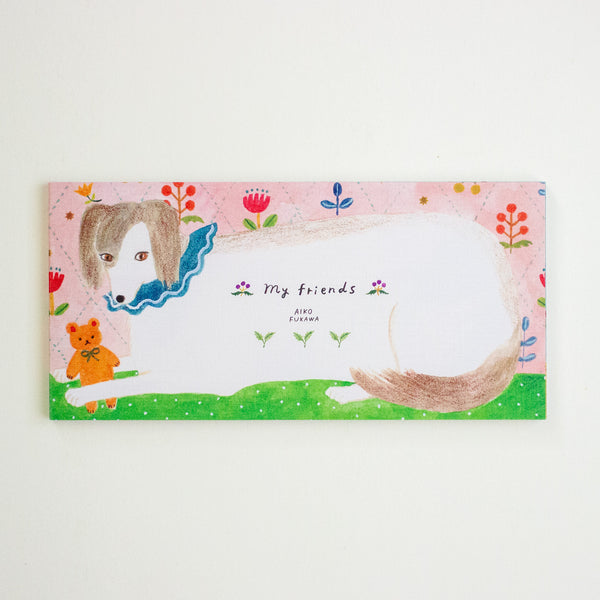 A rectangular illustrated notepad with a pink background, a white cat silhouette, a dog face illustration, green grass, and small floral details. 