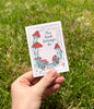 Hand holding a small paper with illustrations of mushrooms on paper with words 'This book belongs to'.
