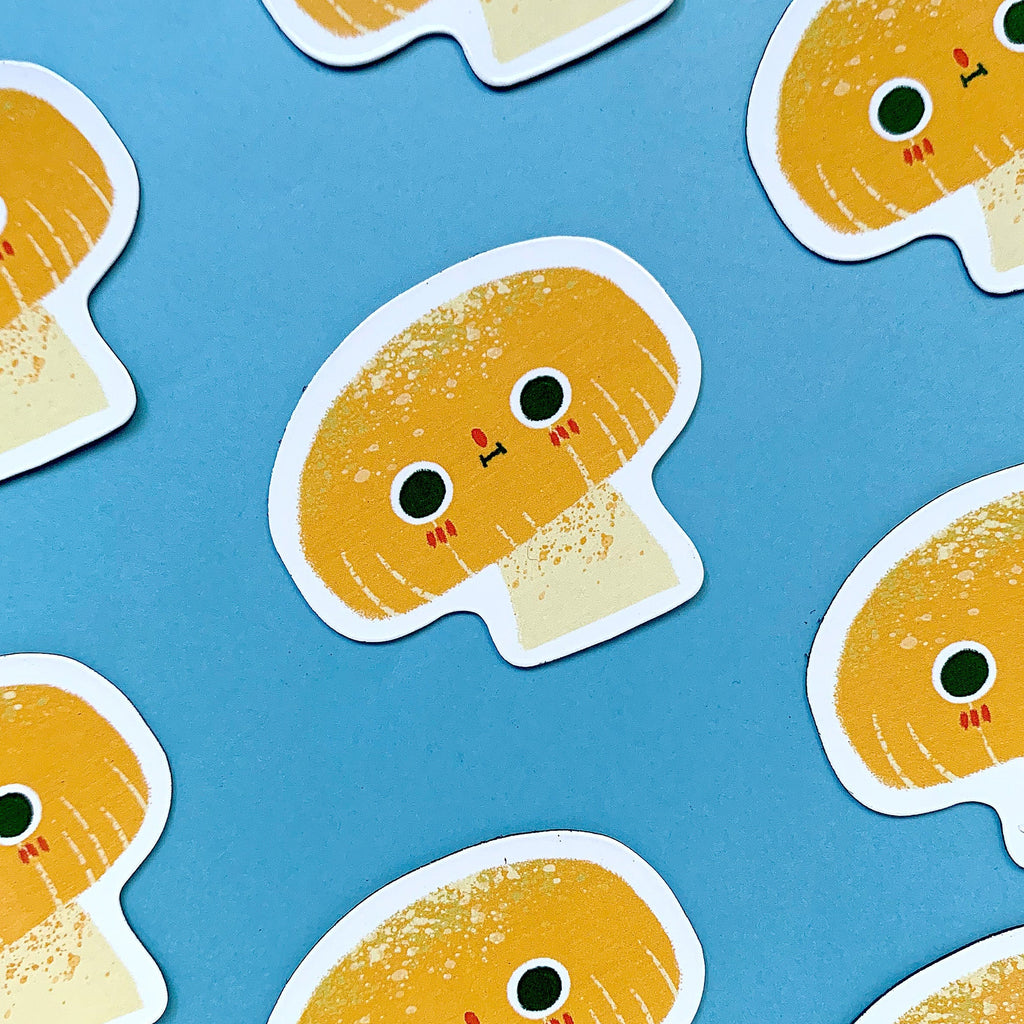 A cute mushroom character magnet with a blue background featuring more of these magnets.