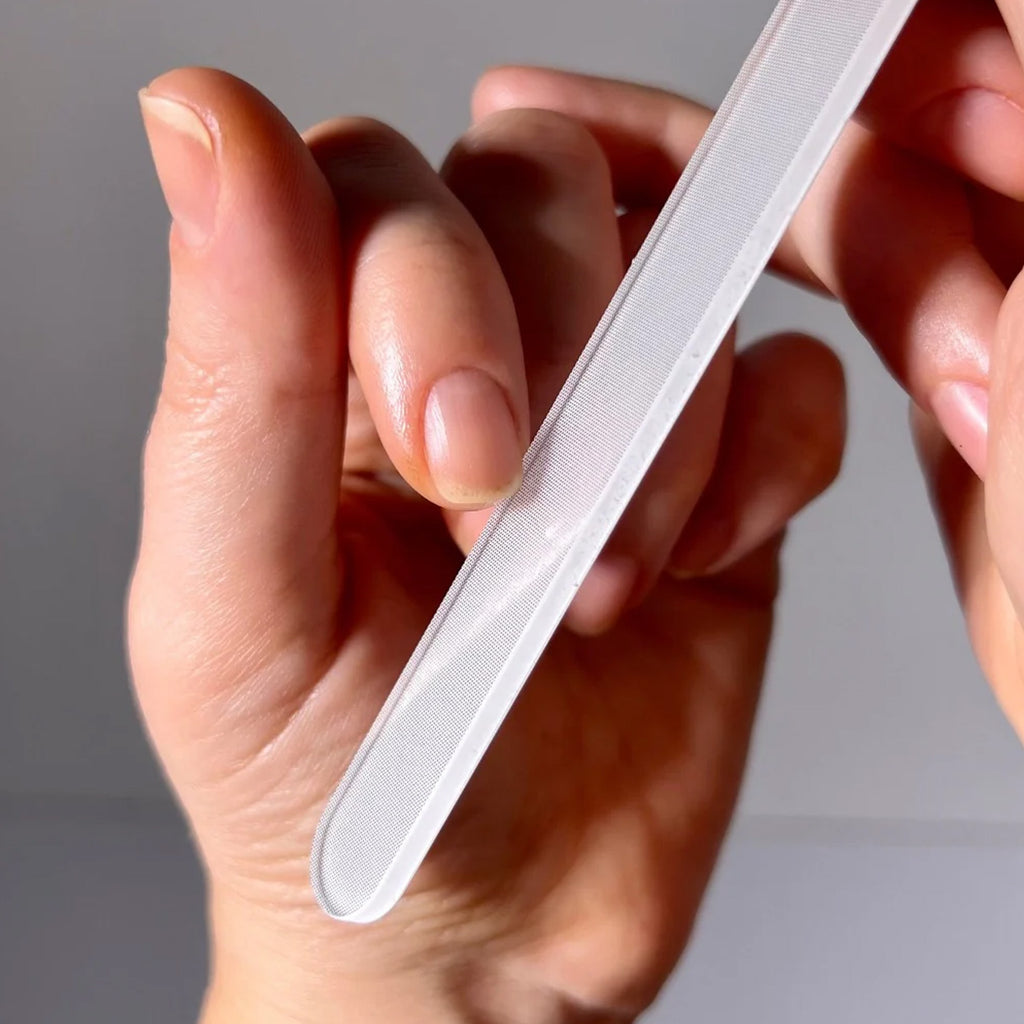Hand holding a glass file against a neutral background