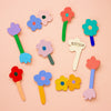 Colourful wooden flower-shaped brooches on a peach background