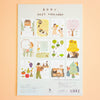 A 2027 calendar with illustrated monthly pages, photographed flat against a soft peach background. The cover shows the title '2027 calendar' in Japanese and English, plus small cover artwork and text blocks.