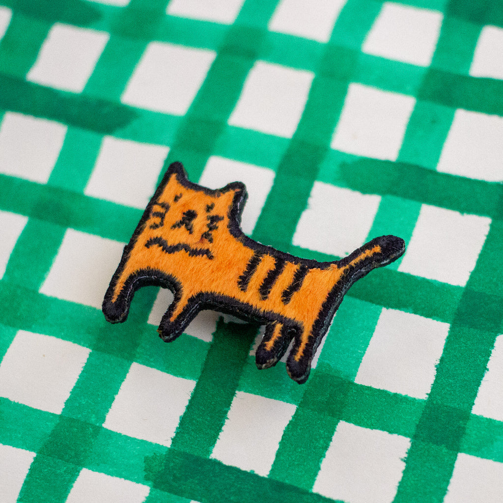 Embroidered patch of a cat on a green and white checkered background