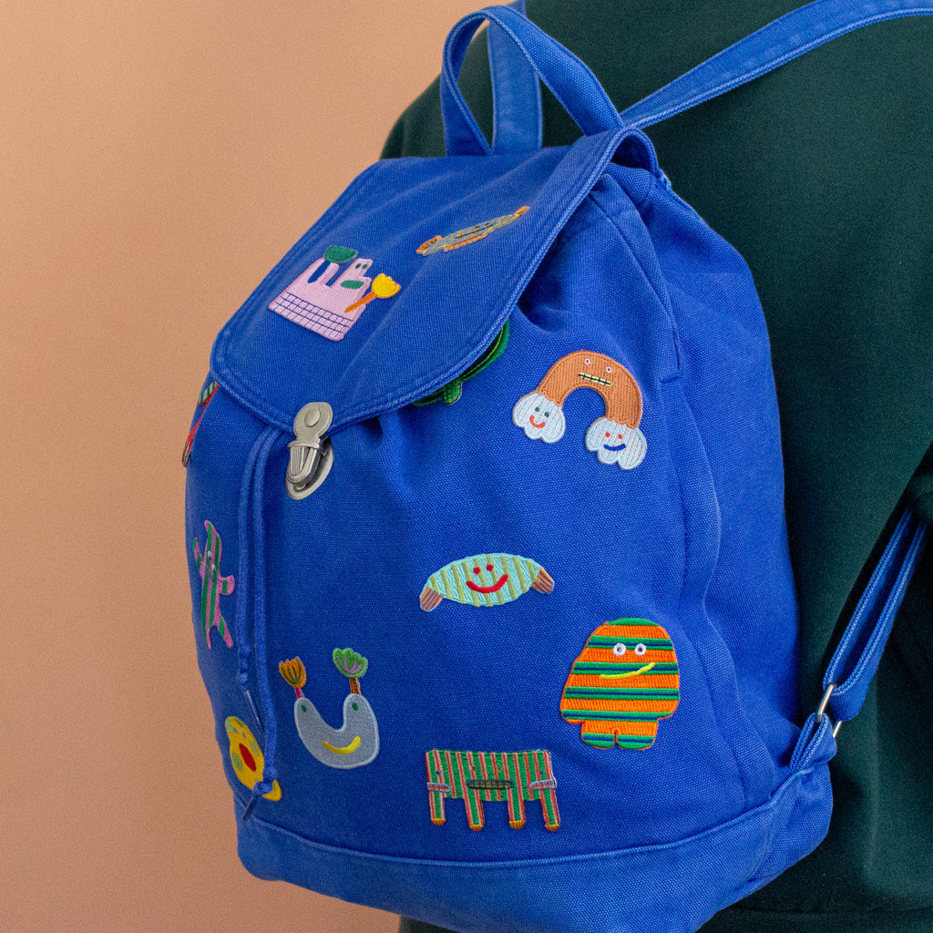 Blue backpack with colorful embroidered designs on a peach background