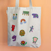 White tote bag with colorful embroidered patches on a peach background