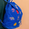 Blue backpack with colorful patches on a peach background