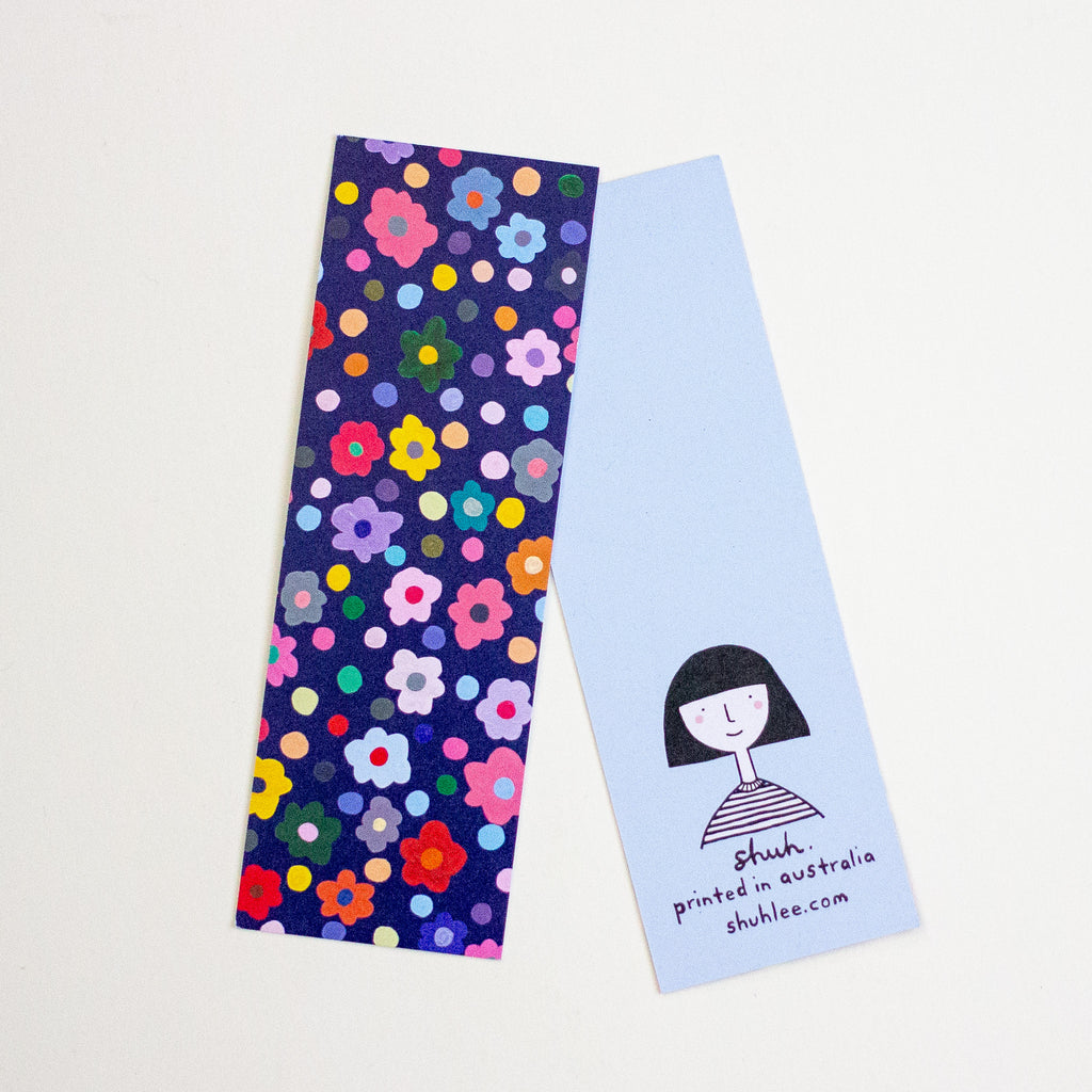 Two bookmarks on a white background. One bookmark has a dark navy blue background covered in a dense pattern of small, colourful flowers and dots.